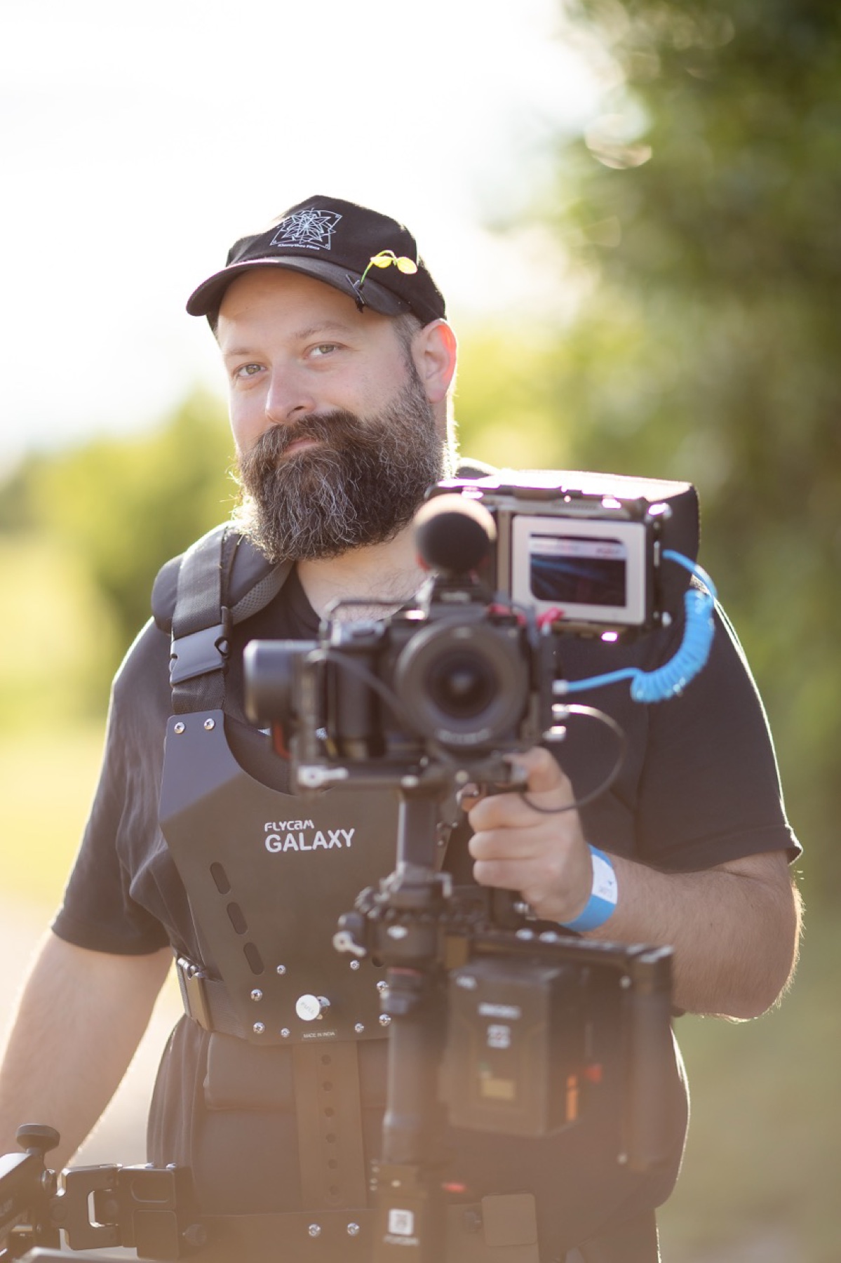 Kiamythos Films camera operator working with a cinema rig outdoors at an event.